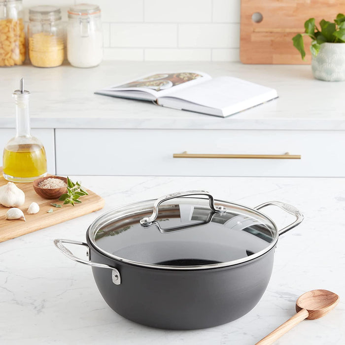  Cuisinart 650-26CP Chef's Classic Nonstick Hard-Anodized 5-Quart Chili Pot with Cover,Black in kitchen with wooden cutting board, olive oil , wooden spoon. Open cookbook is in background next to another wood cutting board with jars of various cooking ingredients