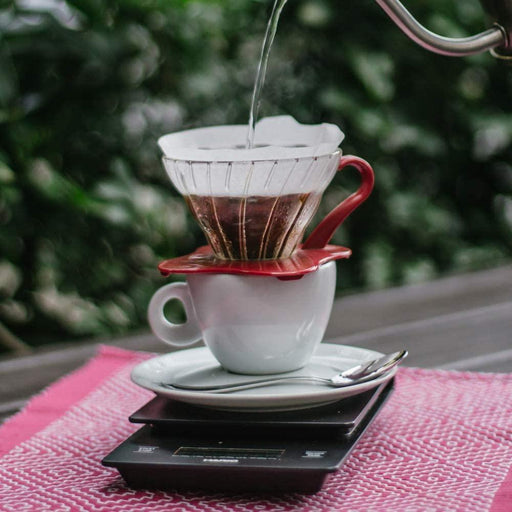 Hario V60 Glass Coffee Dripper, Size 01, Red, outside with pourover on top of scale and white porcelain cup with plate and spoon
